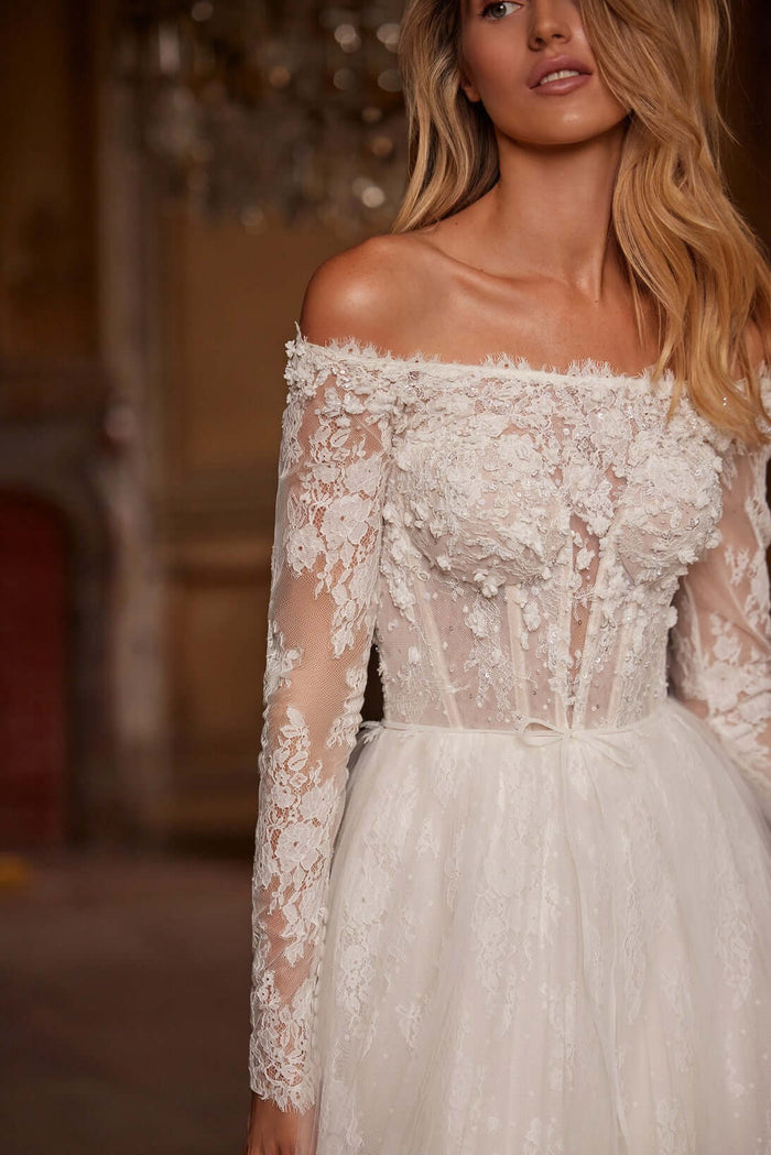 Elegant lace wedding gown with off-shoulder, long sleeves, and intricate floral details.