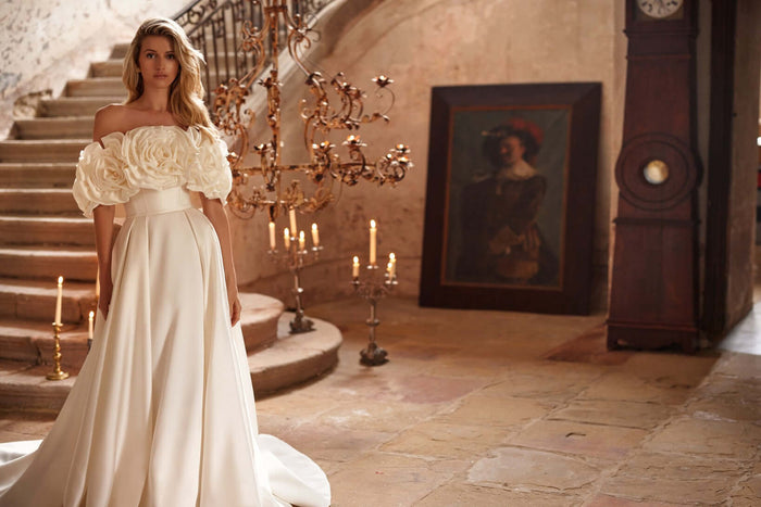 Margery plain satin wedding dress with floral off-shoulder sleeves in an elegant setting.