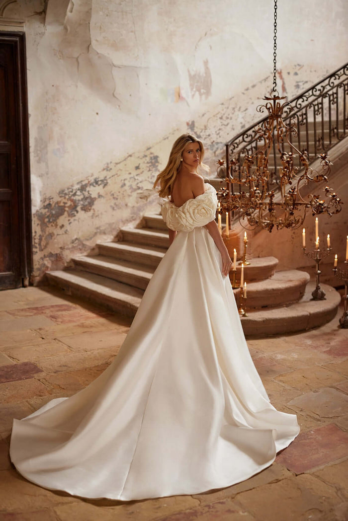 Elegant bride in a Margery plain satin wedding dress with a long train and open shoulder design.