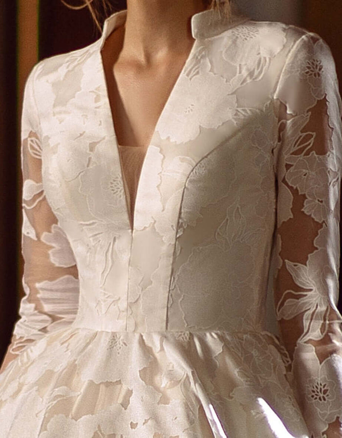 Close-up of Raisa Aline Wedding Dress with long sleeves and V neckline in floral lace fabric.
