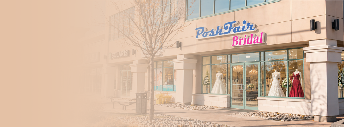 Posh Fair Bridal storefront on a beige building with large windows displaying wedding dresses, including a white gown and a red gown, with a soft warm haze over the left side.
