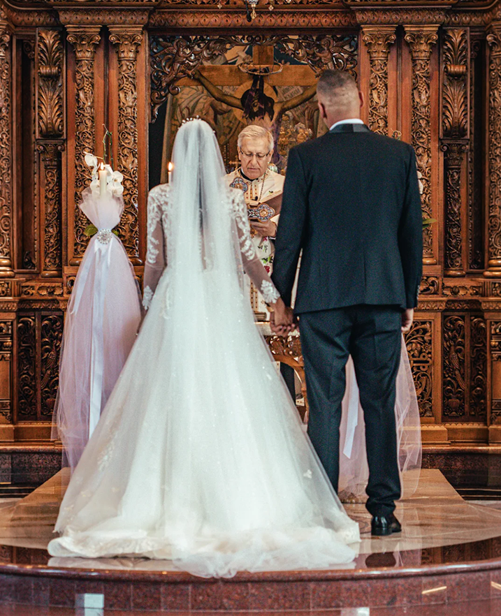 Real bride wearing a custom wedding dress and long veil during a church ceremony