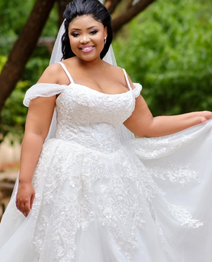 Real Poshfair bride wearing an off-shoulder lace custom wedding dress outdoors